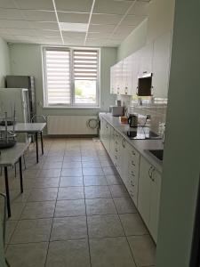 a kitchen with white cabinets and a tile floor at Wielobranżówka in Szepietowo