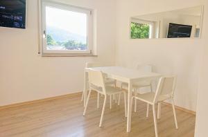 - une table et des chaises blanches dans une chambre avec fenêtre dans l'établissement GreenCorner - Sonnige Terrasse 1-6p, à Reichenbach