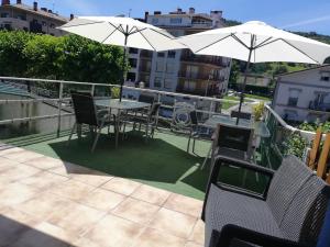 patio ze stołami, krzesłami i parasolami na balkonie w obiekcie Txokomaitea w mieście Urnieta