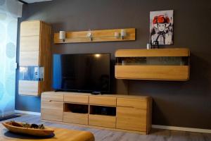ein Wohnzimmer mit Fernseher und einem Entertainment-Center aus Holz in der Unterkunft Schwarzwald geht immer Fewo 60 qm mit großem Südbalkon, WLAN und Magenta TV in Schönwald