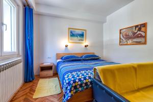 - une chambre avec un lit bleu et une fenêtre dans l'établissement Apartments Margarita, à Mali Lošinj
