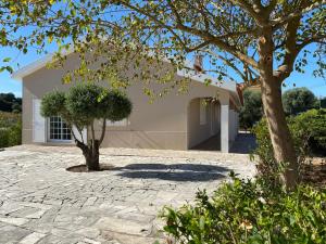 uma casa com uma árvore e uma entrada de pedra em Casal da Rita Campestre em Vaqueiros