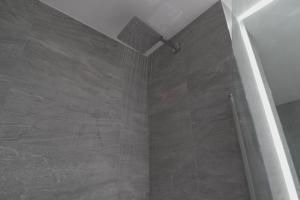a bathroom with a shower with a stone wall at St Albans - Luxury 1 Bedroom Apartment in Saint Albans