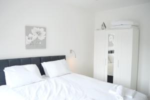 a bedroom with a bed with white sheets and a mirror at St Albans - Luxury 1 Bedroom Apartment in Saint Albans