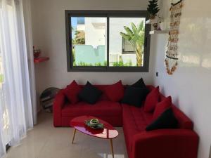 a living room with a red couch and a window at Villa Blanca Beach Pieds-Sur-Mer in Sidi Rahal
