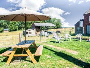 einen Picknicktisch mit einem Regenschirm im Gras in der Unterkunft Plush Holiday Home in Matagne La Petite with Private Garden in Matagne-la-Petite