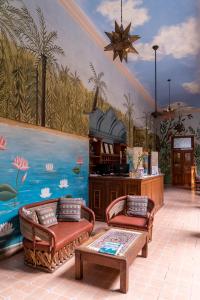 a room with two chairs and a wall with a mural at Hotel Boutique Casa San Angel in Mérida