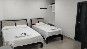 two beds in a room with white sheets at Hotel Jagua Real in La Jagua de Ibirico