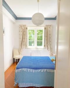a bedroom with a blue bed and a window at Quinta das Tílias in Santiago do Cacém