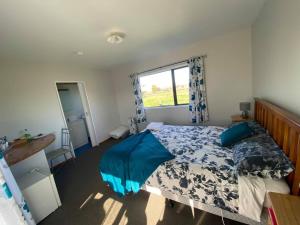 a bedroom with a bed with blue sheets and a window at White Elephant Accomodation in Motueka