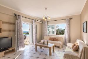 a living room with a couch and a tv at Galini Seaview Kontogialos in Pelekas
