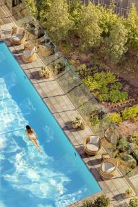 a person swimming in a swimming pool with chairs and a swimming pool at 1 Hotel West Hollywood in Los Angeles
