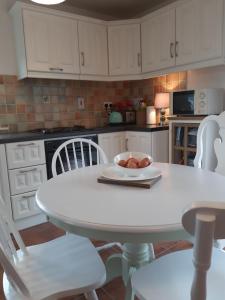 cocina blanca con mesa blanca y sillas en Lorna's Apartment Self Catering Holiday Home, en Miltown Malbay