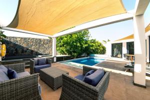 an outdoor patio with wicker chairs and a swimming pool at Casa Yuna with heated pool in El Roque in Cotillo