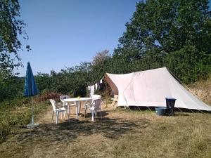a tent with a table and chairs in a field at Camping La Forêt du Morvan in Larochemillay