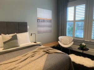 a bedroom with a bed and a chair and a window at Franklin38 in Auckland