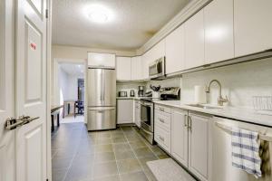a kitchen with white cabinets and a stainless steel refrigerator at JstLikeHome - Central Suite in Ottawa