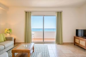 a living room with a couch and a view of the ocean at Clube Porto Mos - Sunplace Hotels & Beach Resort in Lagos