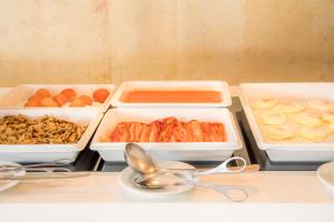 three trays of food on a counter with bowls and spoons at Clube Porto Mos - Sunplace Hotels & Beach Resort in Lagos
