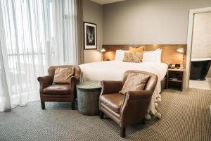 a hotel room with a bed and two chairs at King and Queen Hotel Suites in New Plymouth