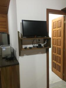 a television on a stand in a room with a door at Caminhos da Serra do Tabuleiro - Chalé Araucária in São Bonifácio