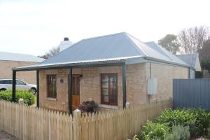 a small brick house with a wooden fence at Victoria Cottage in Robe