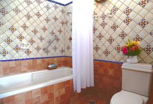a bathroom with a tub and a toilet with a vase of flowers at Quinta Don Jose Boutique Hotel in Guadalajara