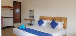 a bedroom with a large white bed with blue pillows at Paretto Seaview Hotel in Pantai Cenang
