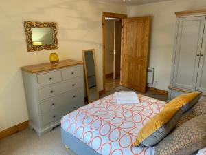 a bedroom with a bed and a dresser and a mirror at The Old Dairy in Lairg