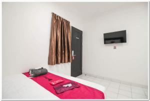 Habitación con cama con manta roja y puerta negra en RedDoorz @ Ruko ITC Roxy Mas, en Yakarta