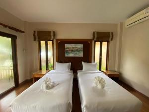 1 Schlafzimmer mit 2 Betten mit weißer Bettwäsche und Fenstern in der Unterkunft Chaithalay Khanom Resort in Ban Phang Phrao