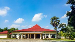 una casa con techo rojo y una palmera en Pendopo 45 Resort en Bogor