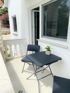 a table and chairs on a balcony with a window at Villa Maluma in Rogoznica
