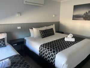 a hotel room with two beds and a picture on the wall at Bega Motel in Bega