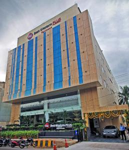 duży budynek z samochodami zaparkowanymi przed nim w obiekcie Best Western Plus Tejvivaan w mieście Visakhapatnam