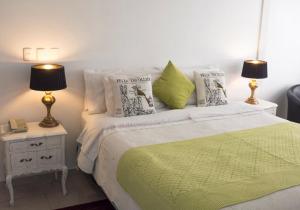 a bedroom with a bed with a green blanket and two lamps at Vip Home in Santiago