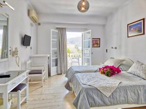 una camera con un letto e una scrivania con fiori di Avraki a Kamari