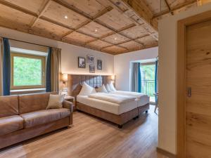 una camera da letto con un letto e un divano di Alpen Glück Hotel Unterm Rain garni a Kirchberg in Tirol