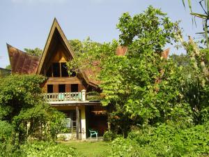 a house with a thatched roof and trees at Liberta Homestay in Tuktuk Siadong