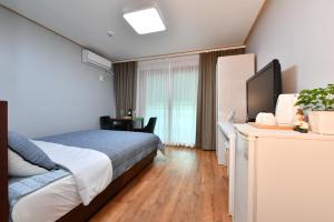 a bedroom with a bed and a desk with a television at Naksanstay in Yangyang