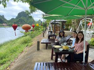 Tres mujeres sentadas en una mesa con comida. en Son Doong Riverside en Phong Nha