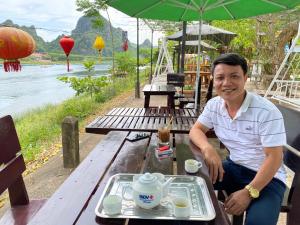 un hombre sentado en una mesa con una bandeja de comida en Son Doong Riverside en Phong Nha