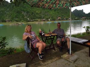 a man and a woman sitting at a table by a lake at Son Doong Riverside in Phong Nha