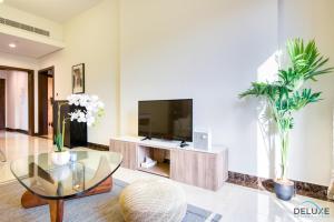 a living room with a tv and a glass table at Eclectic 1BR in Pantheon Boulevard by Deluxe Holiday Homes in Dubai