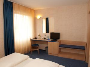 a hotel room with a bed and a desk with a computer at Hotel Chassalla in Kassel