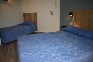 um quarto com uma cama azul e um edredão azul em Cat'Hotel em Bourg-de-Péage