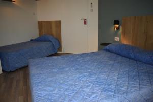 two beds in a hotel room with lights on at Cat'Hotel in Bourg-de-Péage