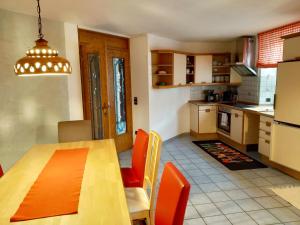 a kitchen with a wooden table and orange chairs at Ferienhaus Marré - mit Grill, Feuerstelle und Gartensauna in Waldbrunn