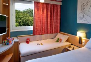 サランにあるibis Orléans Nord Saranのベッド2台と窓が備わる小さな客室です。