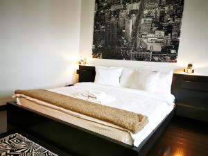 a bedroom with a large bed with a picture on the wall at Sector 6 - Metrou Gorjului - Studio G by MRG Apartments in Bucharest